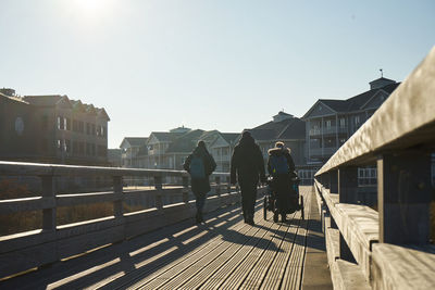 Rear view of people walking on street against clear sky