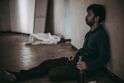 Side view of young man sitting at home