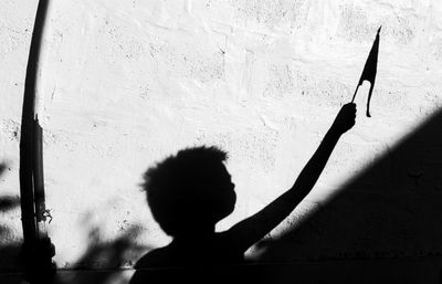 Shadow of boy holding flag on wall