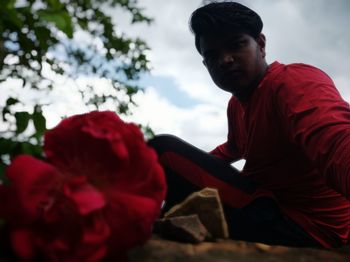 Rear view of man looking at red flower