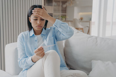 Young woman using mobile phone while lying on bed at home