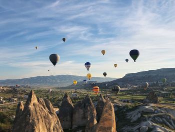 Hot air balloons flying over rocks against sky