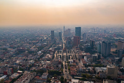 Aerial view of city buildings against sky during sunset