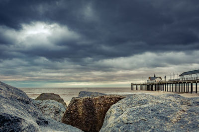 Rocks at beach against cloudy sky