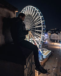 Man with ferris wheel in city at night