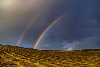 Scenic view of rainbow over mountain against sky