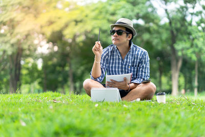 Young man using mobile phone while sitting on field