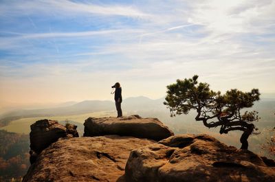 Silhouette woman standing on cliff against sky