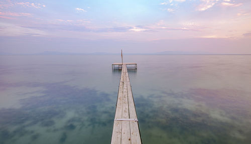 Pier over sea against sky during sunset