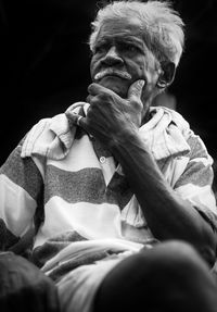 Low angle view of man sitting against black background