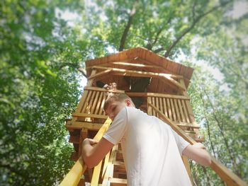 Low angle view of man holding umbrella against trees