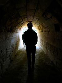 Silhouette man standing in tunnel