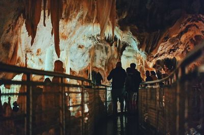 Rear view of people standing in cave