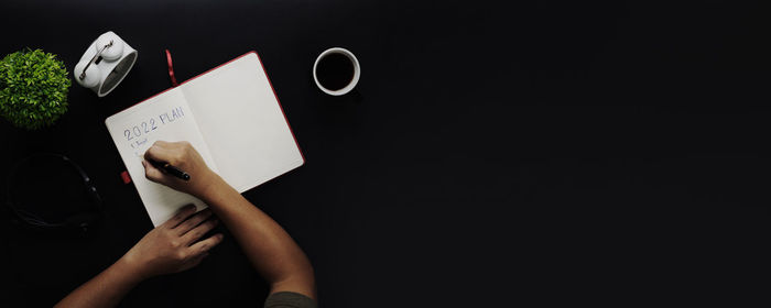 Midsection of woman holding paper against black background