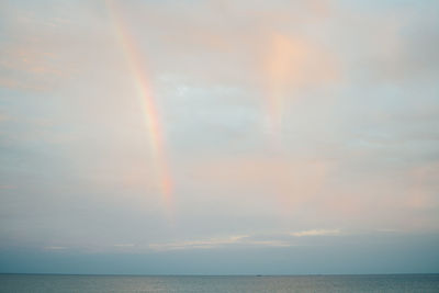 Scenic view of rainbow over sea against sky