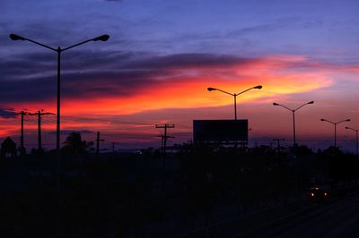 Silhouette street against sky during sunset