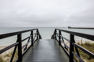 Empty wooden jetty leading to sea against sky