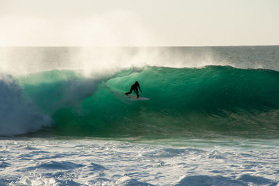 Person surfing in sea against sky