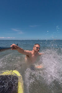 Man surfing in sea against sky