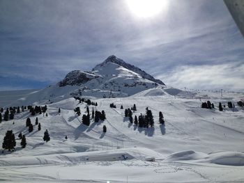 Panoramic view of people on snow covered landscape against sky