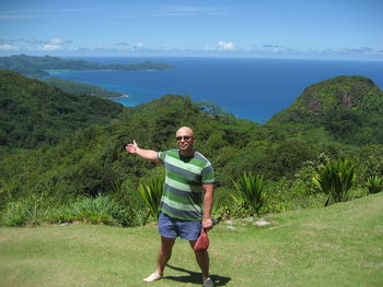 Full length of smiling man standing on mountain against sky