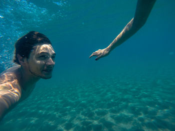 Cropped image of woman with man swimming in sea