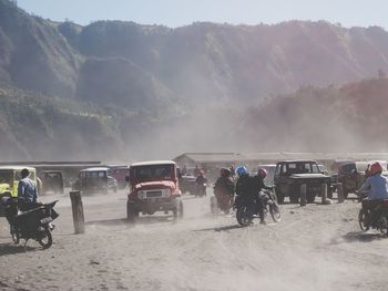 People on road by mountains against sky