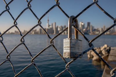 Close-up of chainlink fence against lake toronto 