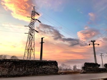 Silhouette electricity pylon against dramatic sky during sunset