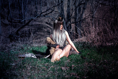 Rear view of woman sitting in forest