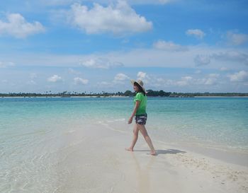 Full length of woman standing on beach against sky