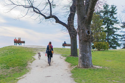 Rear view of woman walking with dog on footpath