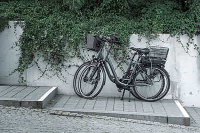 Bicycle parked on sidewalk by wall