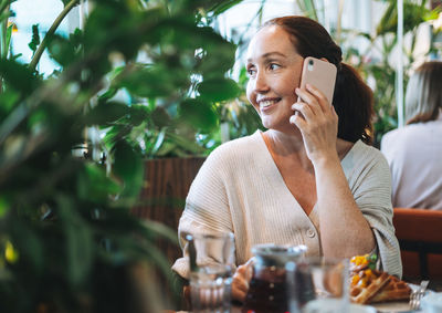 Young woman using mobile phone while sitting on table