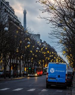 Road by trees against sky in city