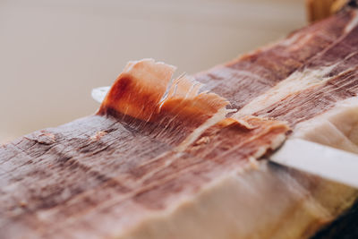 From above view of knife cutting thin slice of ham with tallow lines