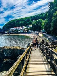 People walking on footbridge against sky