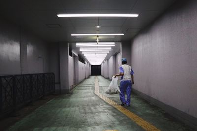 Rear view of man walking in illuminated corridor