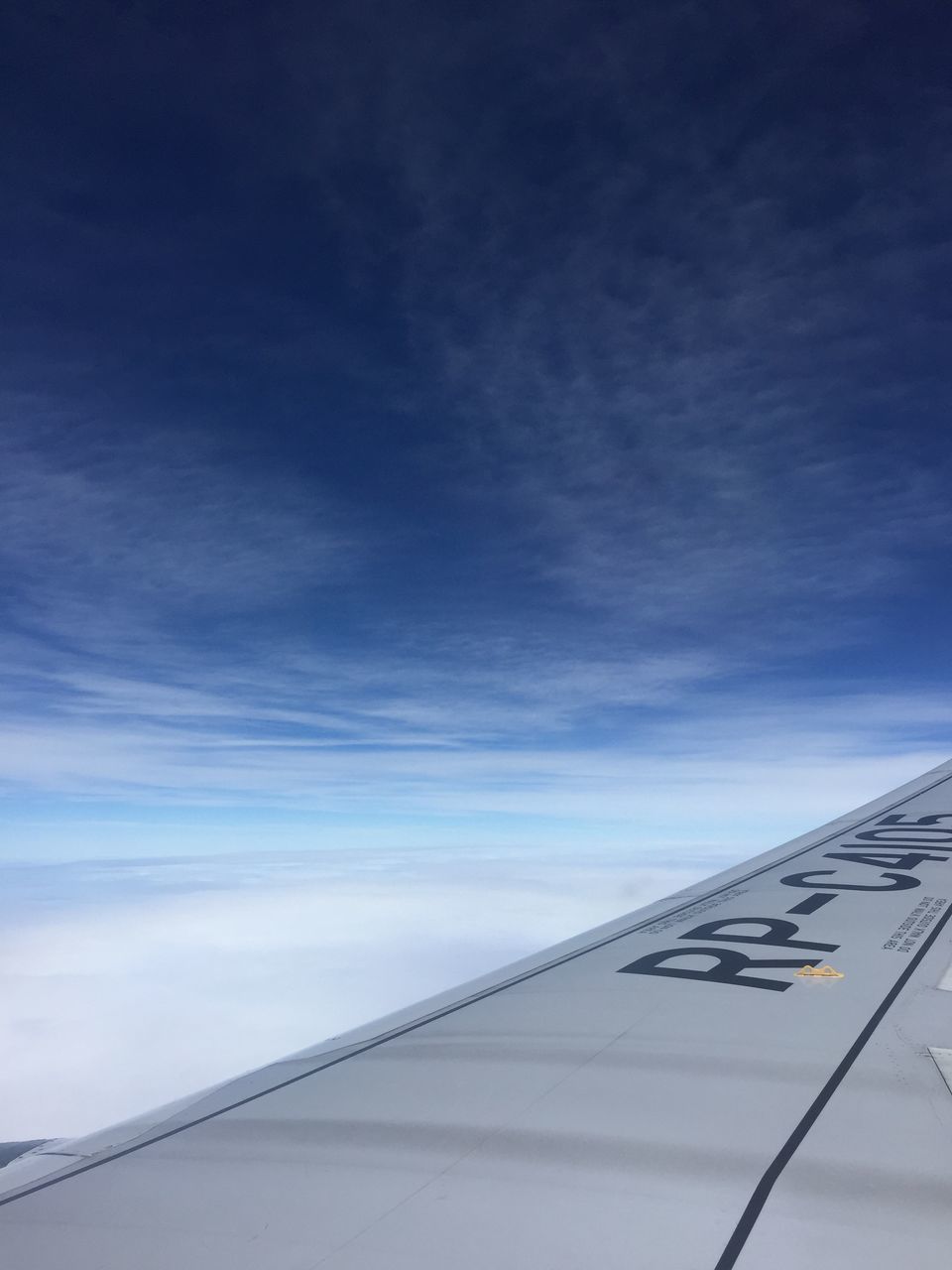 AIRPLANE WING OVER CLOUDS AGAINST SKY