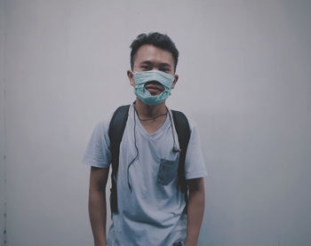 Portrait of young man wearing torn mask against wall