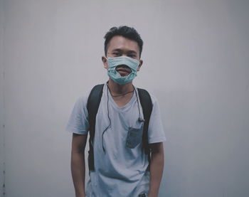 Portrait of young man standing against wall