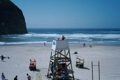 People at beach against clear blue sky