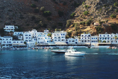 Sailboats moored on sea by buildings in city