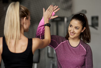 Trainer doing high-five with woman in gym