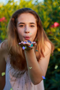 Portrait of young woman blowing confetti