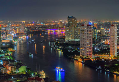 High angle view of illuminated buildings by river against sky at night