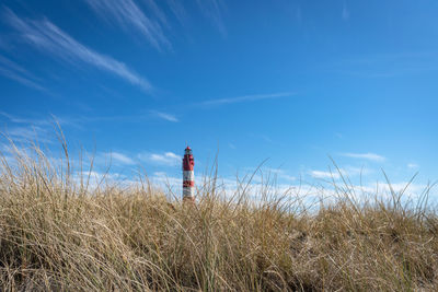 Man standing by lighthouse on land against sky