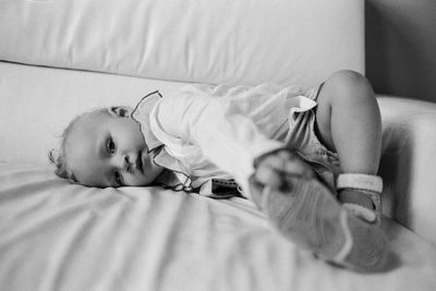 Portrait of cute baby girl lying on sofa