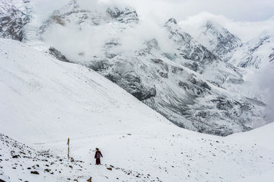 Rear view of person walking on snow covered mountain