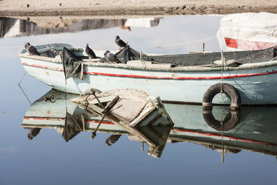 Fishing boats moored in lake against sky